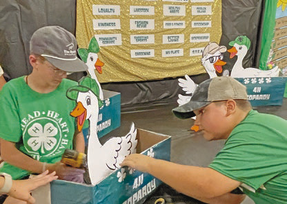 Levi Humble (from left), 11, and Henry Chaumont, 10, put the finishing touches on the 4-H Blazers Homeschool Club’s “4-H Jeopardy” booth for the Jeff Davis Parish Fair booth competition.