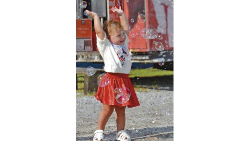 Everleigh Sye Marie Ortego, 18 months, celebrates the July 4 holiday in downtown Jennings. Ortego excitedly danced in the barrage of bubbles provided by the Bubble Bus. Daily News photo by Erin Hargrave