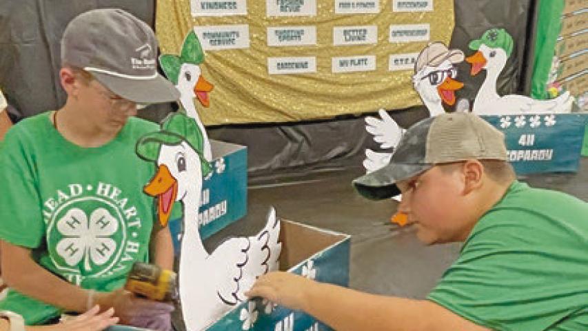Levi Humble (from left), 11, and Henry Chaumont, 10, put the finishing touches on the 4-H Blazers Homeschool Club’s “4-H Jeopardy” booth for the Jeff Davis Parish Fair booth competition.